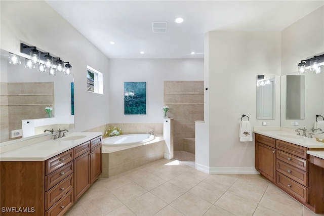 bathroom featuring tile patterned flooring, vanity, and tiled tub