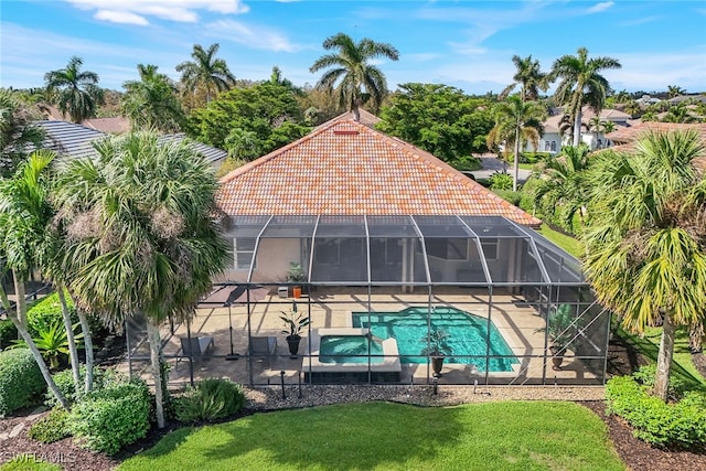 view of pool with glass enclosure, a lawn, and a patio area