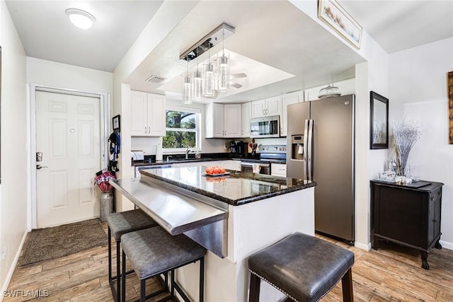 kitchen with decorative light fixtures, a center island, light hardwood / wood-style floors, stainless steel appliances, and white cabinets