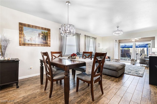 dining area featuring hardwood / wood-style flooring and ceiling fan with notable chandelier