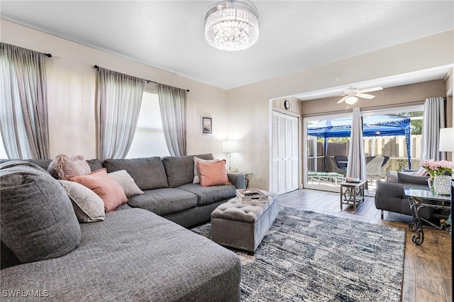 living room featuring ceiling fan with notable chandelier and hardwood / wood-style floors