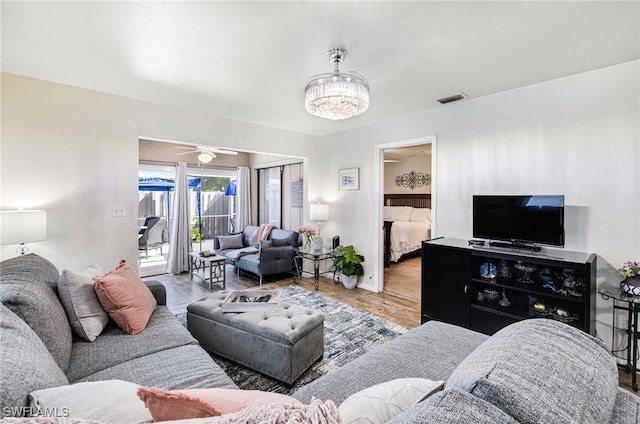 living room featuring wood-type flooring and ceiling fan with notable chandelier