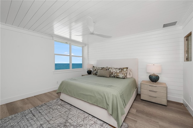 bedroom featuring a water view, ceiling fan, light hardwood / wood-style floors, and wooden ceiling