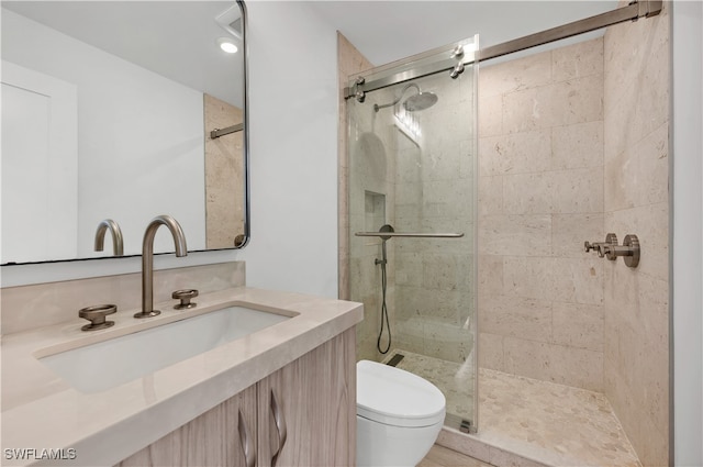 bathroom with toilet, vanity, and a shower with shower door