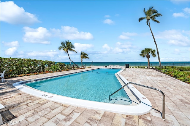 view of pool with a patio area and a water view