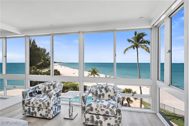 sunroom / solarium featuring a water view, a healthy amount of sunlight, and a view of the beach