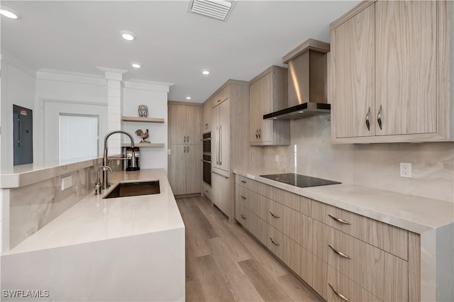 kitchen with black electric stovetop, sink, light brown cabinets, and wall chimney range hood