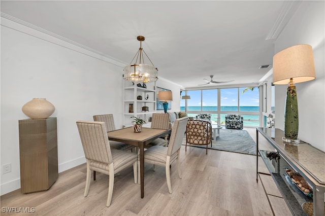 dining area with floor to ceiling windows, a water view, light hardwood / wood-style floors, ornamental molding, and ceiling fan with notable chandelier