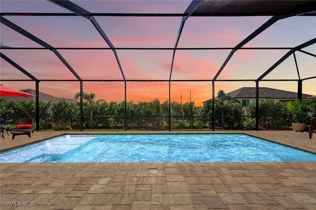 pool at dusk with a lanai and a patio