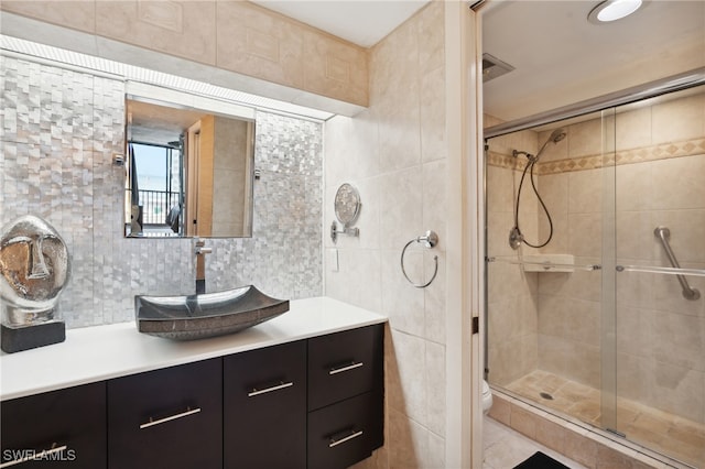 bathroom featuring tile walls, vanity, backsplash, and a shower with shower door