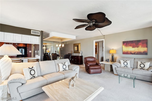 living room with ceiling fan with notable chandelier and light colored carpet