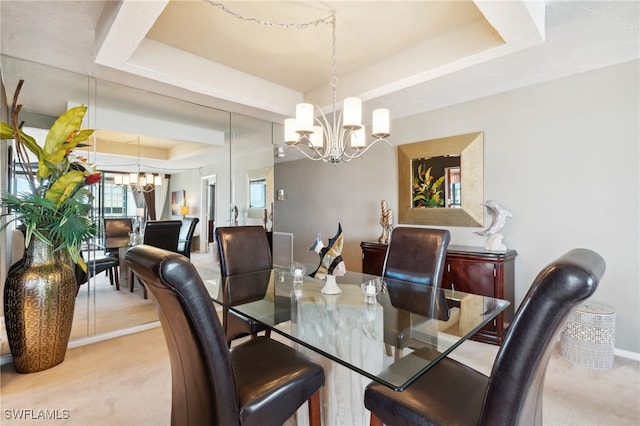 dining area with light carpet, a chandelier, and a tray ceiling