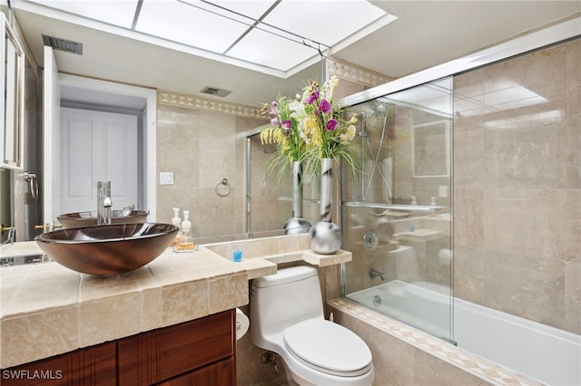 full bathroom with toilet, vanity, and bath / shower combo with glass door