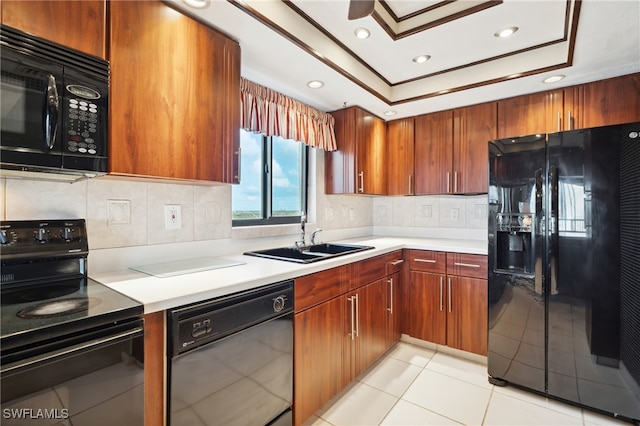 kitchen with sink, black appliances, light tile patterned floors, a raised ceiling, and decorative backsplash