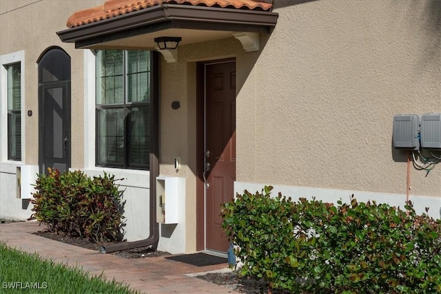 doorway to property with stucco siding and a tile roof