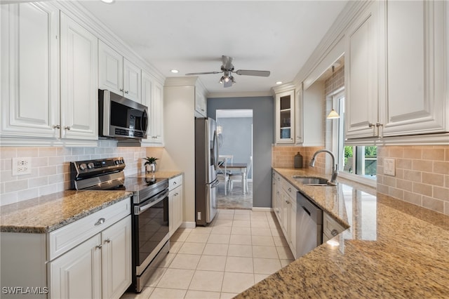 kitchen with appliances with stainless steel finishes, light stone counters, ornamental molding, sink, and white cabinets