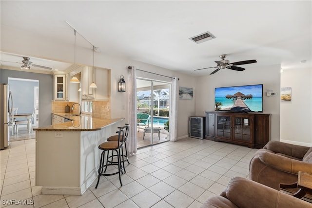 kitchen with kitchen peninsula, decorative backsplash, light stone counters, pendant lighting, and a breakfast bar area