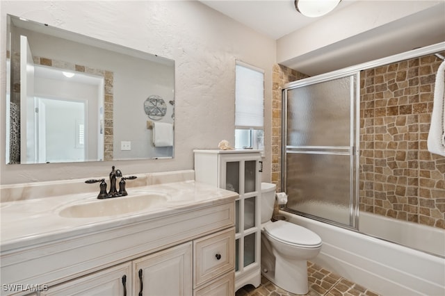 full bathroom with vanity, bath / shower combo with glass door, and toilet