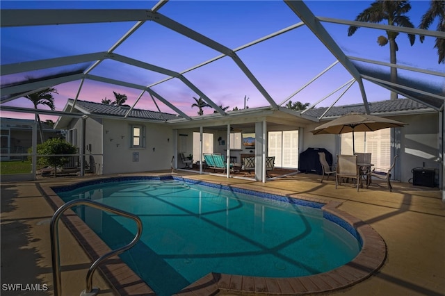 pool at dusk featuring a patio area and glass enclosure