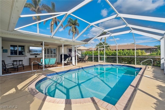 view of pool with ceiling fan, a lanai, and a patio