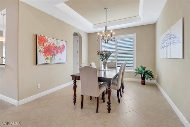 dining room featuring a tray ceiling, an inviting chandelier, ornamental molding, and light tile patterned flooring