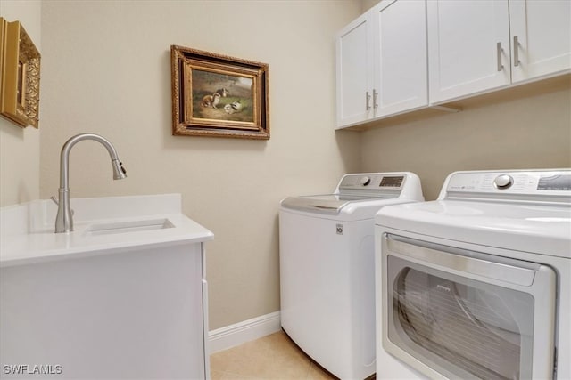 laundry area with sink, light tile patterned floors, cabinets, and independent washer and dryer