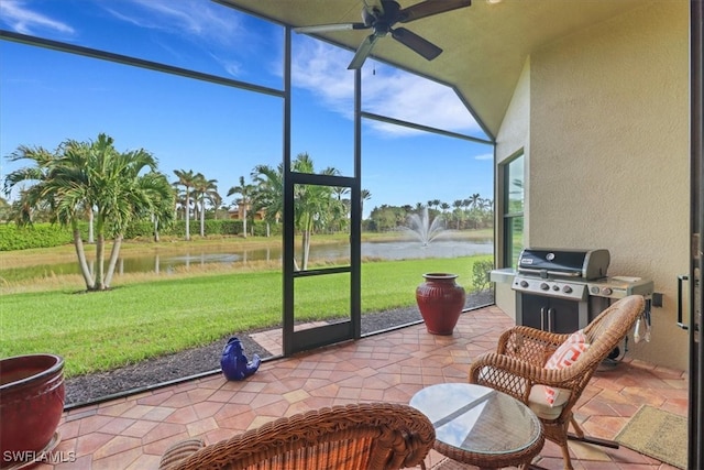 sunroom featuring ceiling fan and a water view