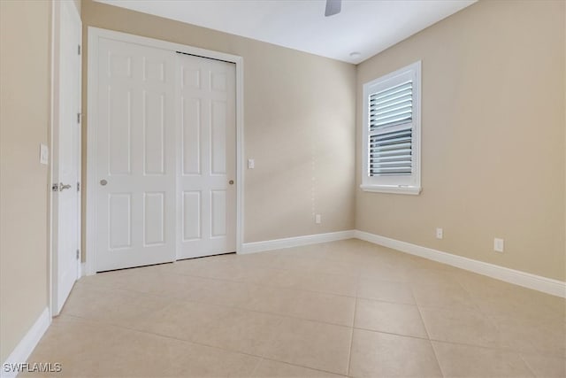 unfurnished bedroom featuring ceiling fan, a closet, and light tile patterned floors