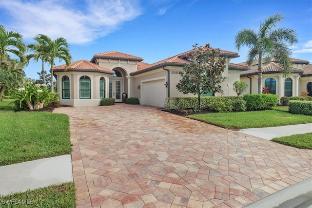 mediterranean / spanish-style home featuring a front yard and a garage