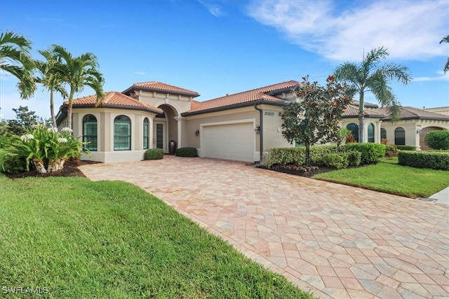 mediterranean / spanish home featuring a garage and a front lawn