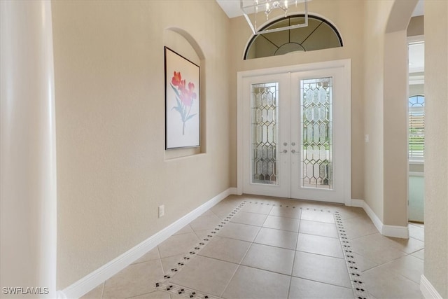 foyer featuring a notable chandelier, light tile patterned floors, and french doors