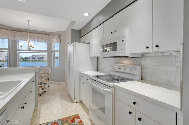 kitchen with white cabinetry, sink, an inviting chandelier, white appliances, and a water view