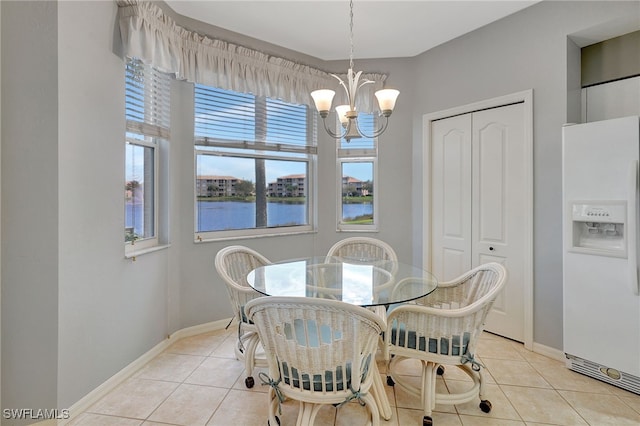 dining space with a water view, light tile patterned flooring, and an inviting chandelier