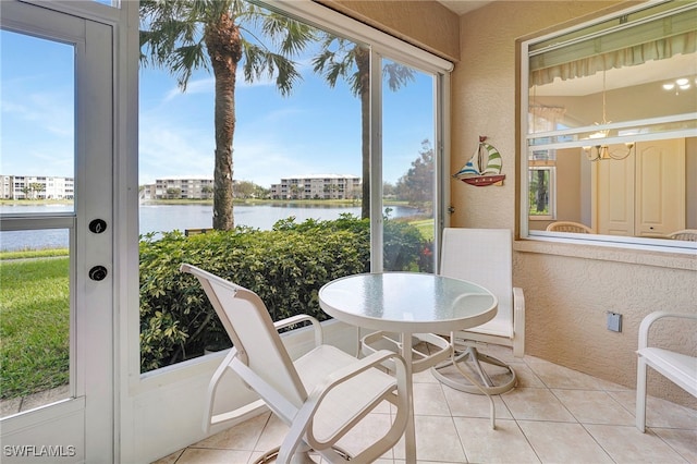 sunroom with a water view, a healthy amount of sunlight, and a notable chandelier