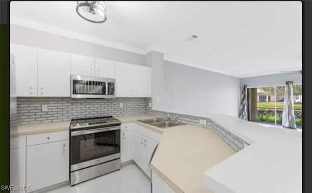 kitchen featuring kitchen peninsula, decorative backsplash, sink, white cabinetry, and appliances with stainless steel finishes