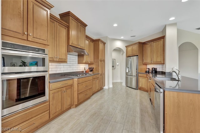 kitchen with sink, backsplash, stainless steel appliances, and light wood-type flooring