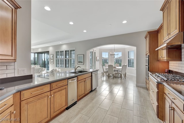 kitchen featuring sink, appliances with stainless steel finishes, decorative backsplash, and pendant lighting