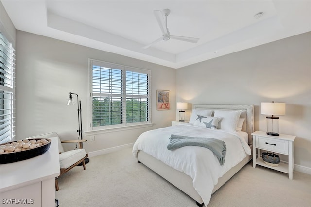 bedroom with ceiling fan, light carpet, and a raised ceiling