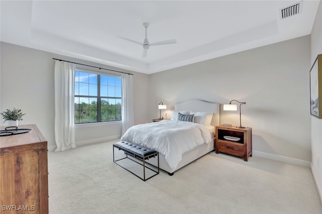 carpeted bedroom featuring ceiling fan and a raised ceiling