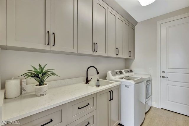 washroom featuring cabinets, washer and clothes dryer, and sink