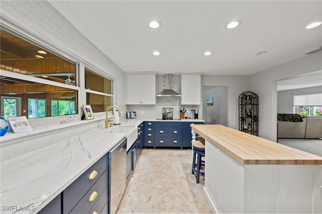 kitchen with a kitchen bar, white cabinetry, plenty of natural light, and wall chimney exhaust hood