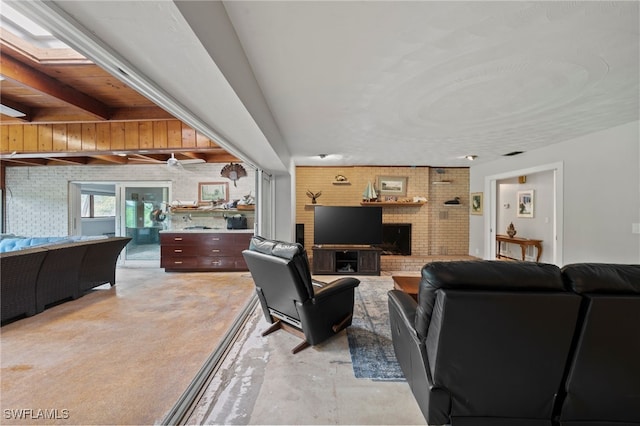 living room with beamed ceiling, a skylight, brick wall, and a brick fireplace