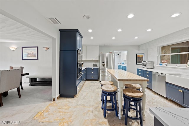 kitchen with stainless steel appliances, blue cabinets, a breakfast bar area, and sink