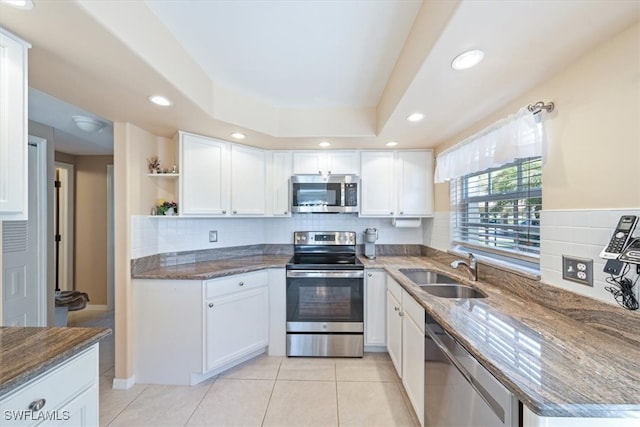 kitchen featuring backsplash, white cabinetry, appliances with stainless steel finishes, light tile patterned floors, and sink