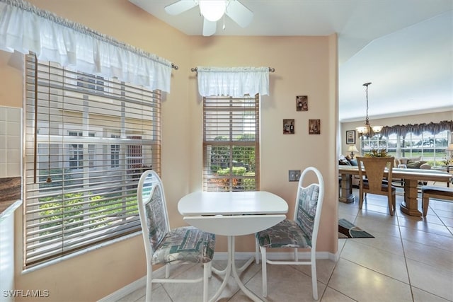 dining room featuring lofted ceiling, tile patterned flooring, a healthy amount of sunlight, and ceiling fan with notable chandelier