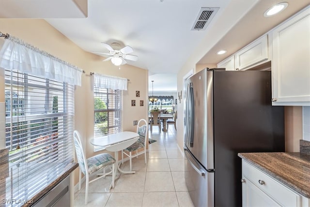 kitchen featuring white cabinets, light tile patterned floors, ceiling fan, dark stone countertops, and stainless steel fridge