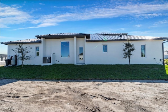 back of property featuring central air condition unit and a yard