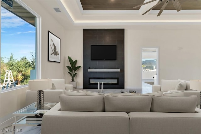 living room with a tiled fireplace, a wealth of natural light, and ceiling fan