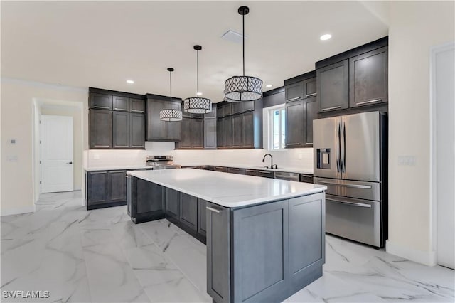 kitchen featuring backsplash, sink, hanging light fixtures, appliances with stainless steel finishes, and a kitchen island