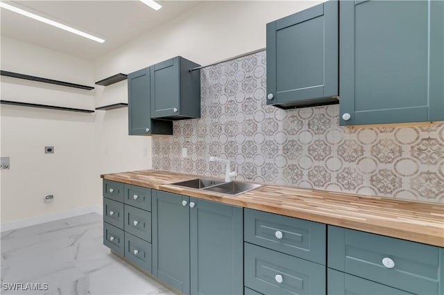 kitchen with tasteful backsplash, butcher block counters, sink, and blue cabinets